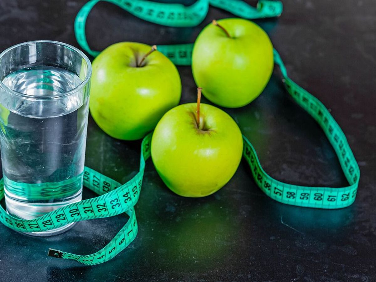 weight loss book on a wooden table with a measuring tape and fresh fruits